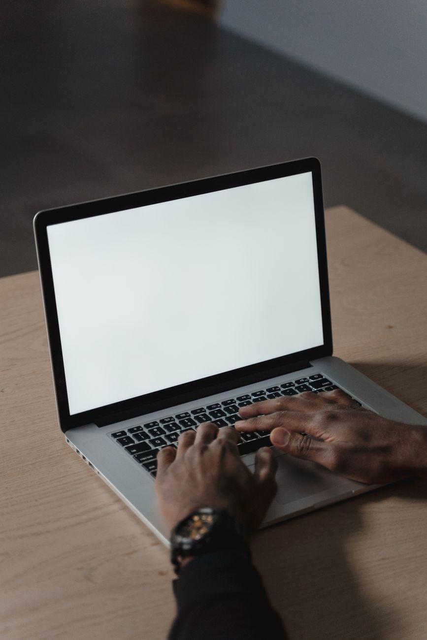 Hænder skriver på en bærbar computer ved et bord